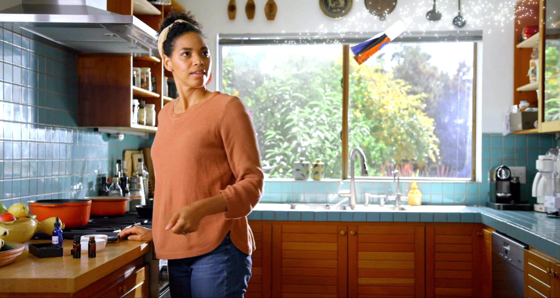 A woman is standing in a kitchen in front of a window.