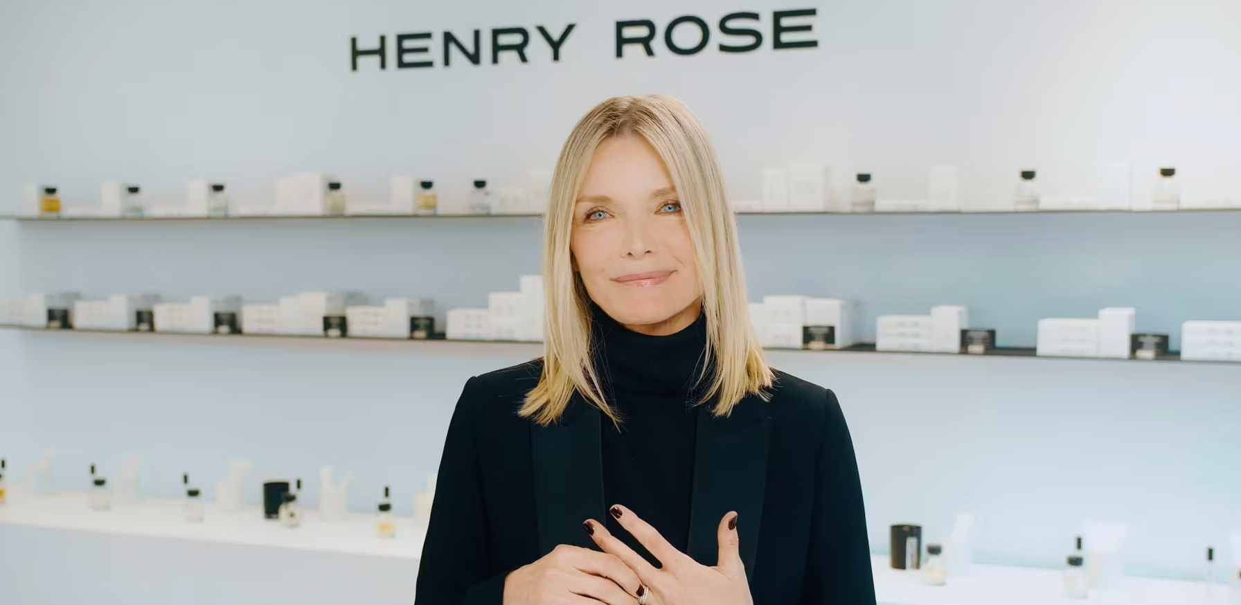 A woman is standing in front of a wall that says henry rose.