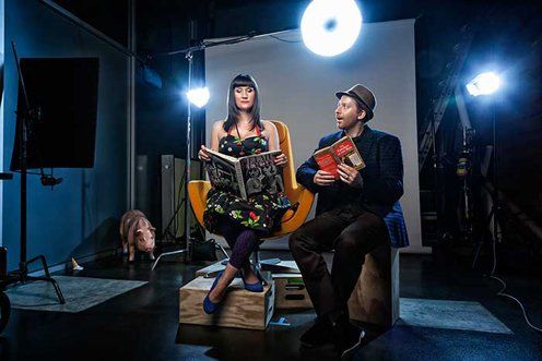 A man and a woman are sitting in a chair holding books.