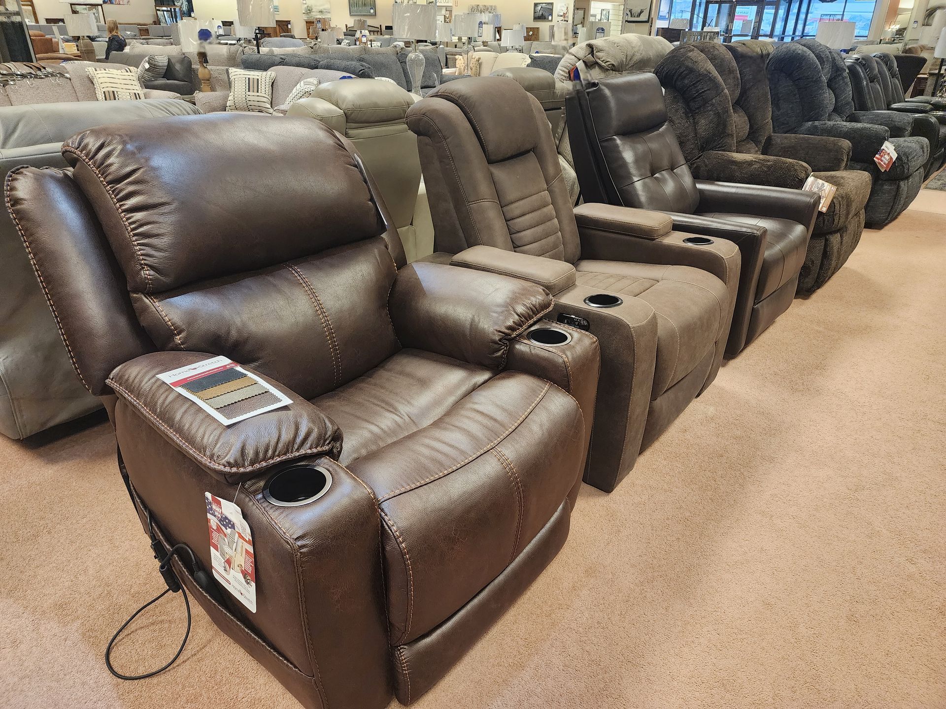 A row of brown leather recliner chairs in a furniture store.