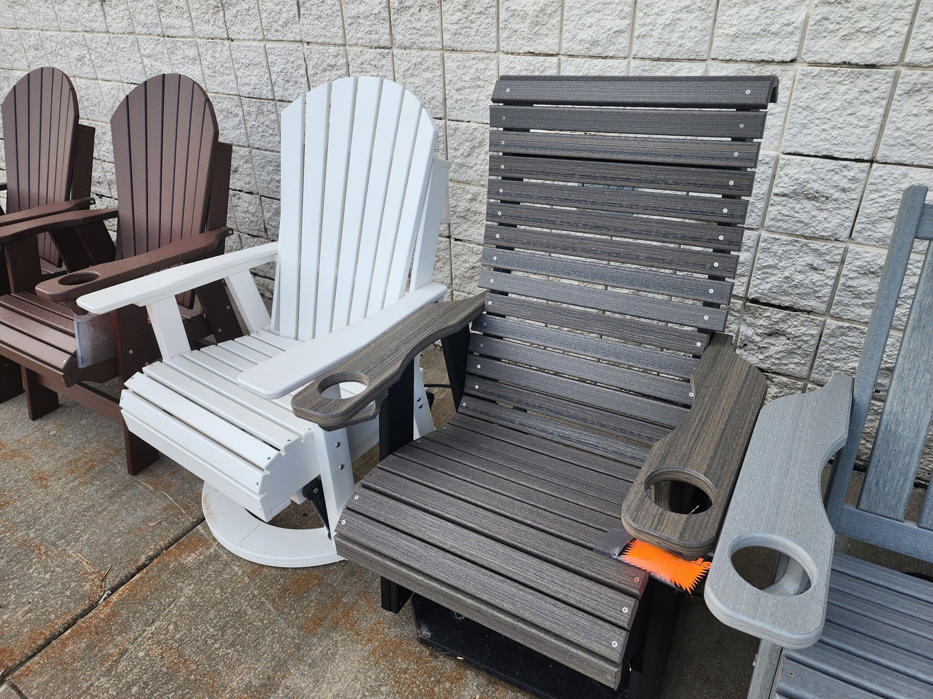 A row of wooden chairs are sitting on a sidewalk in front of a brick wall.