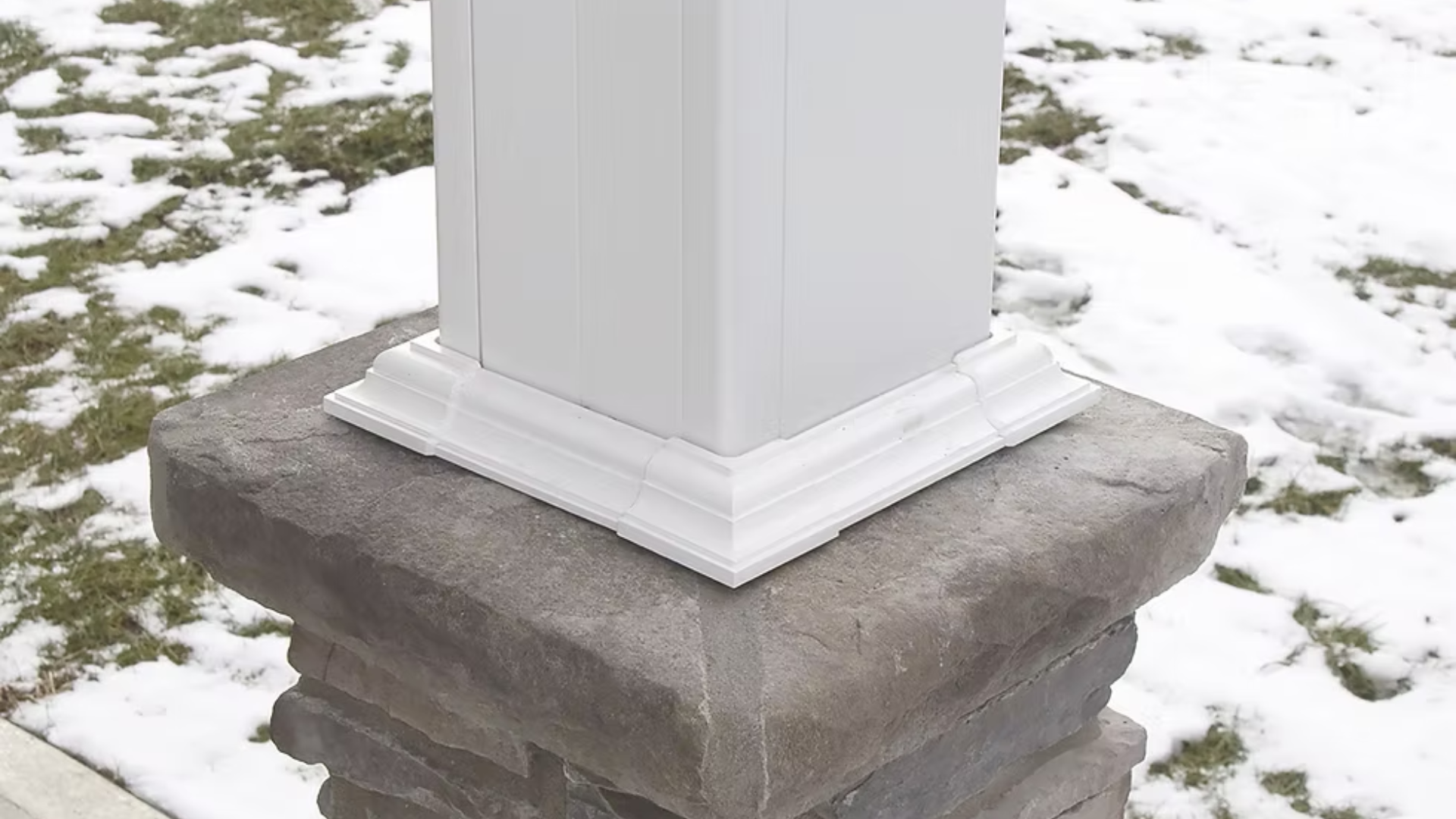 White post on a gray stone base with snow in the background.