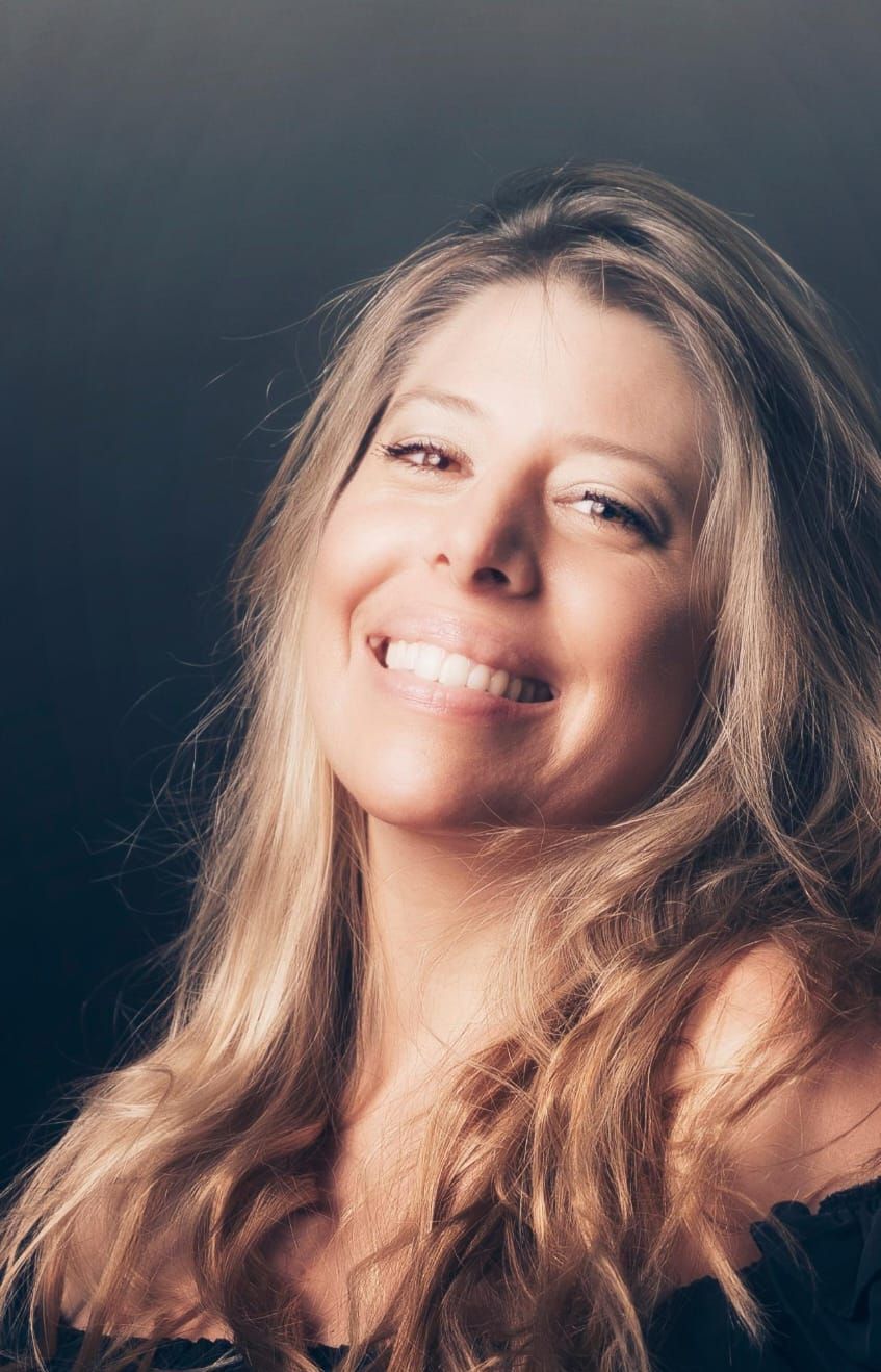 Una mujer con cabello largo y rubio sonríe para la cámara.