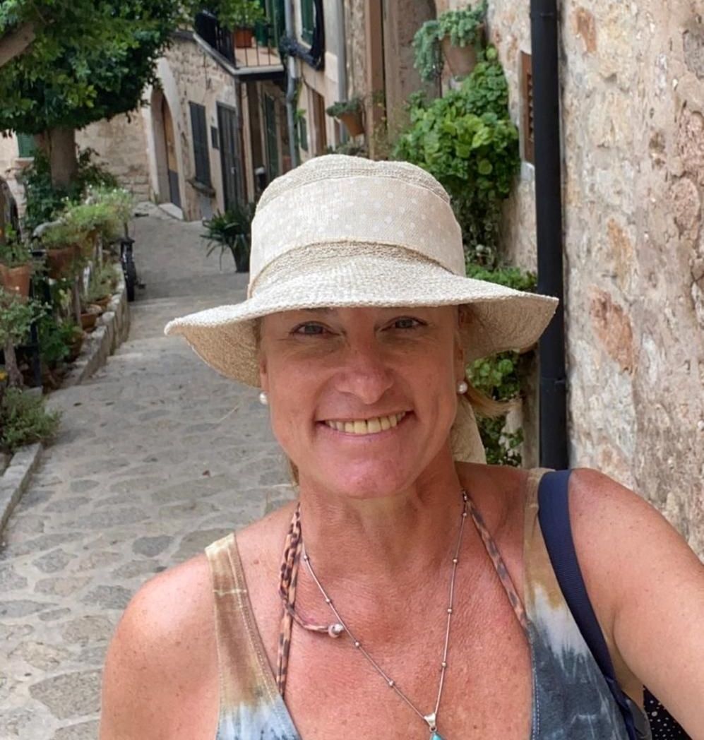 Una mujer que lleva un sombrero y un collar sonríe para la cámara.