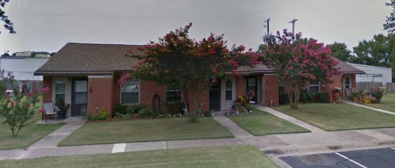 A row of brick houses with trees in front of them.