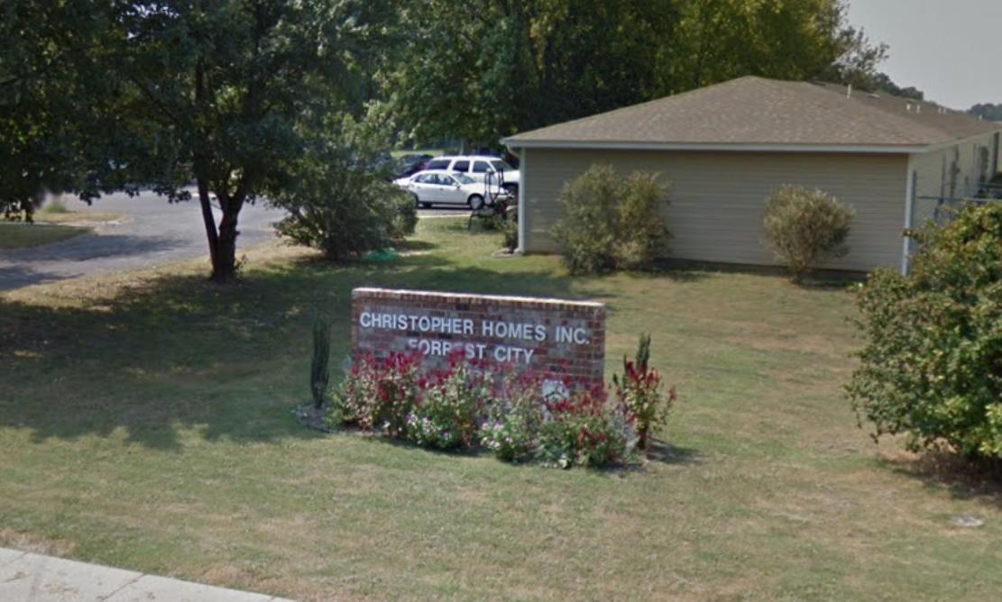 A large sign is in front of a house in a grassy area.