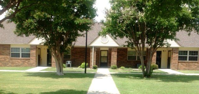A brick apartment building with trees in front of it