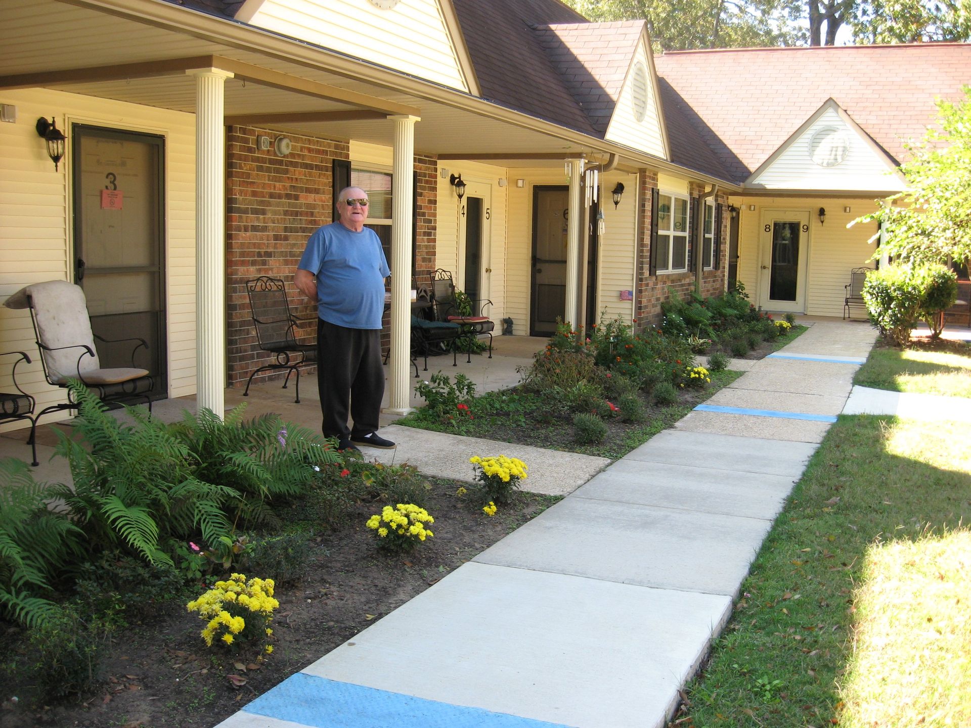 A man standing on a sidewalk in front of a house