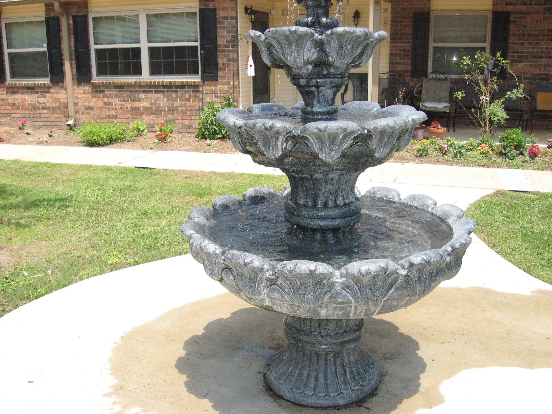 A fountain sits in front of a brick house