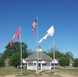 Three flags are flying in front of a gazebo.
