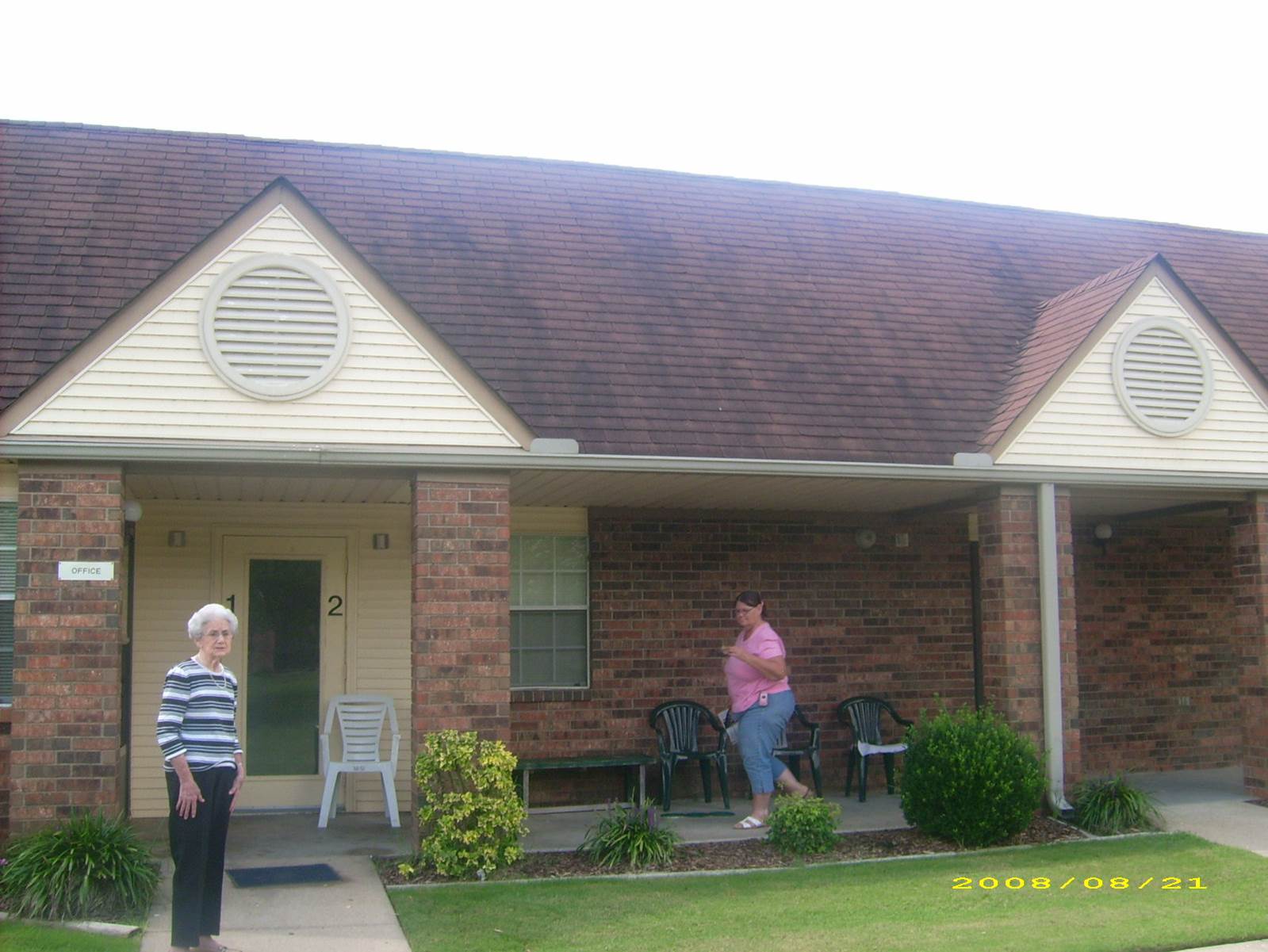 Two women standing in front of a brick house
