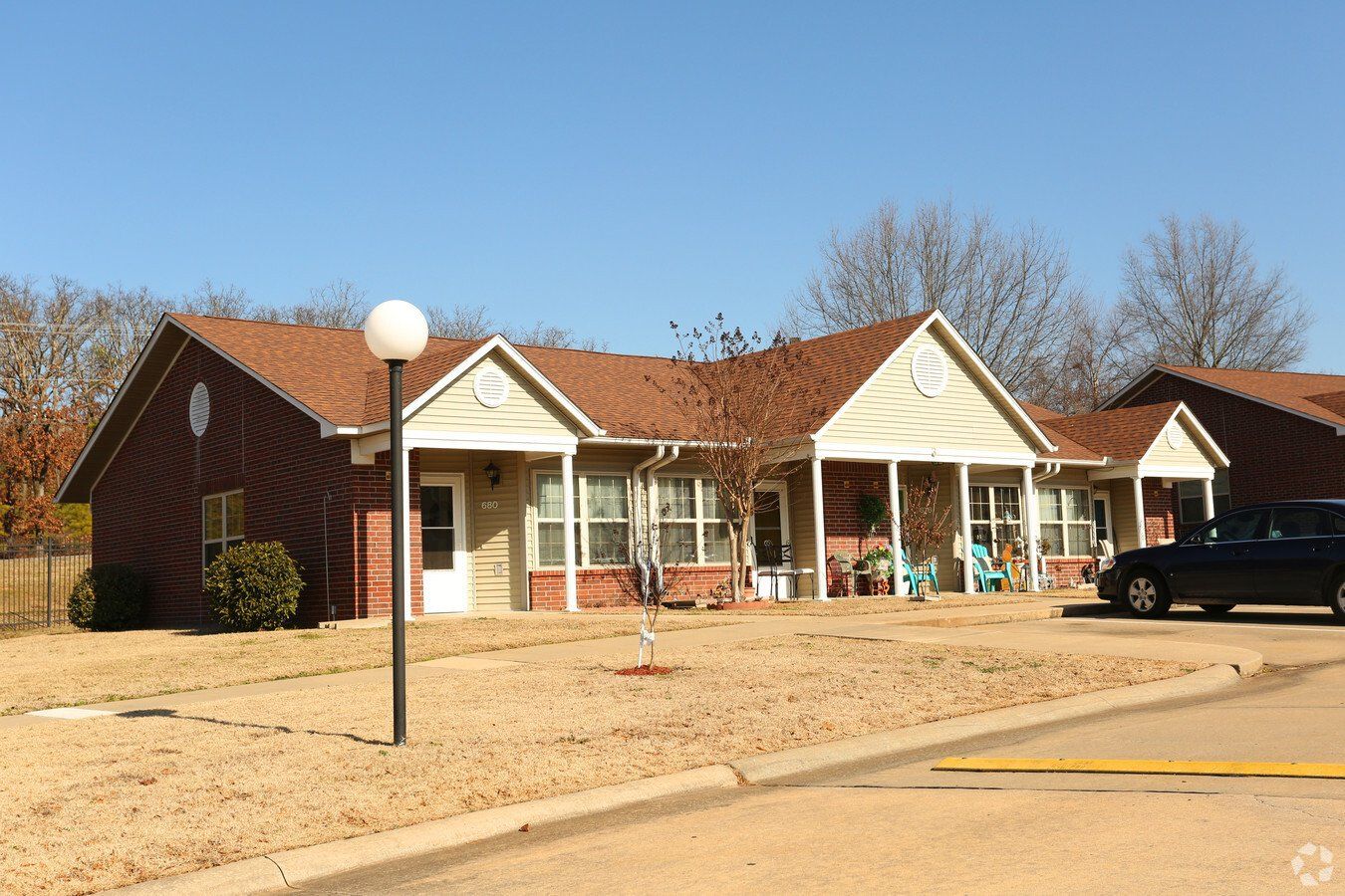 A car is parked in front of a house with a porch.