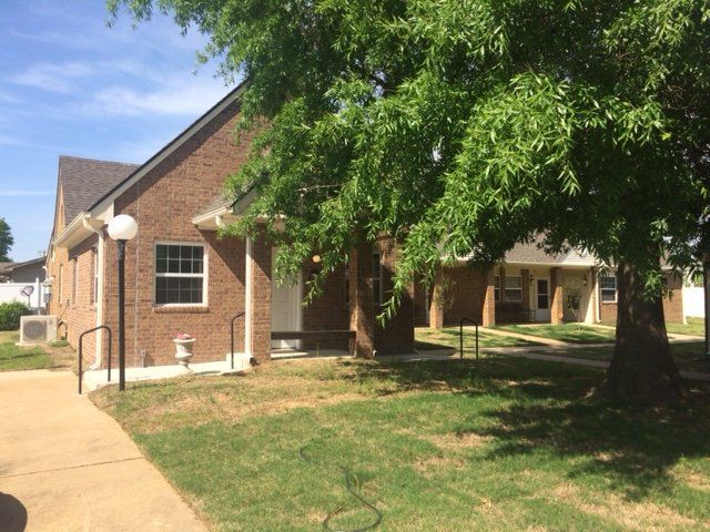 A brick house with a large tree in front of it.