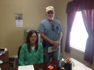 A man standing next to a woman sitting at a desk