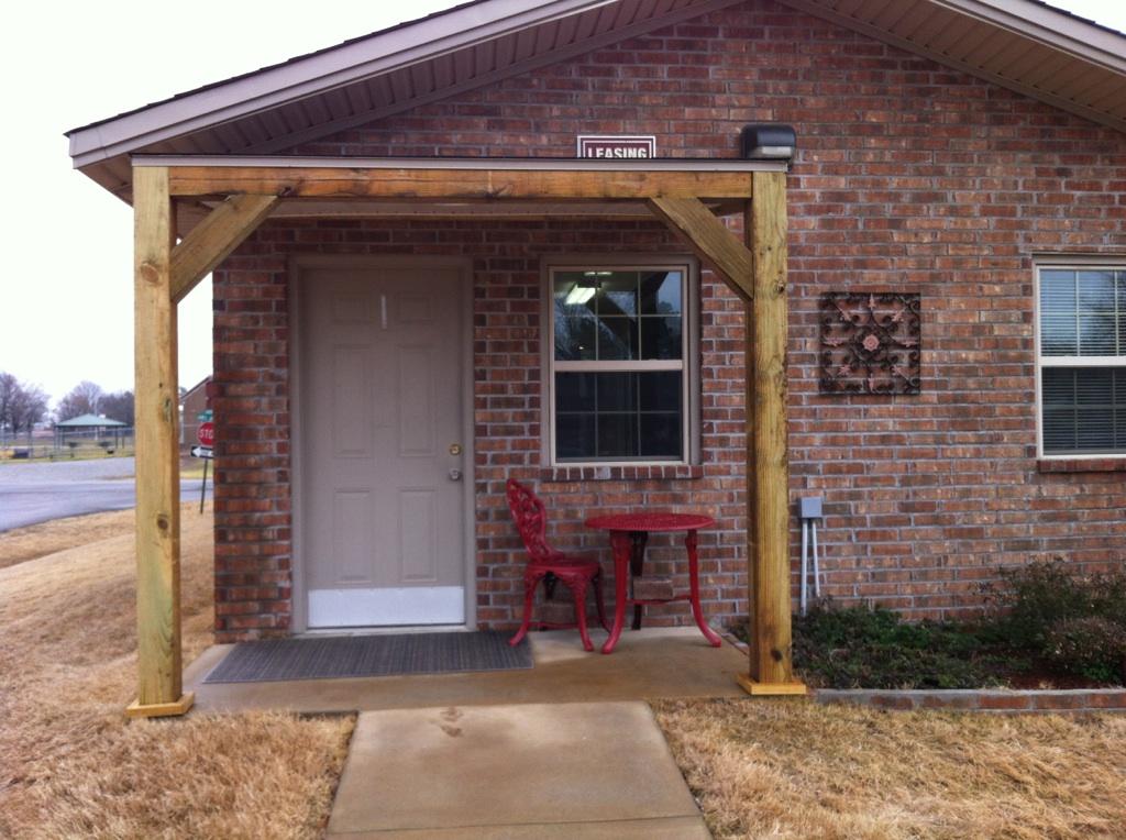 A brick house with a wooden porch and a table and chairs