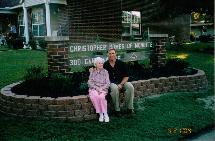 A man and a woman sit in front of a sign that says christopher homes of monette