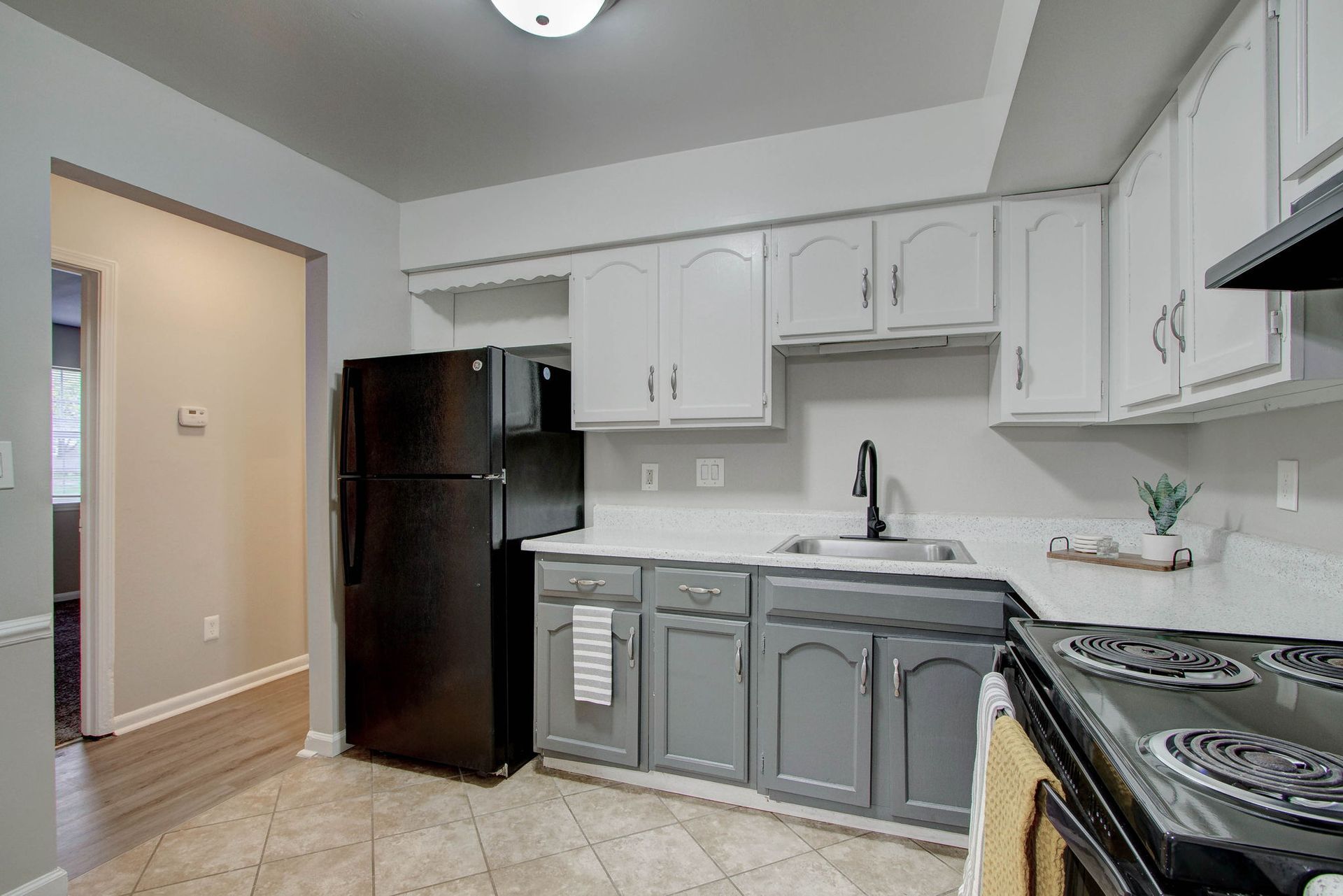 Kitchen with gray and white cabinets, black appliances, and beige tile floor.
