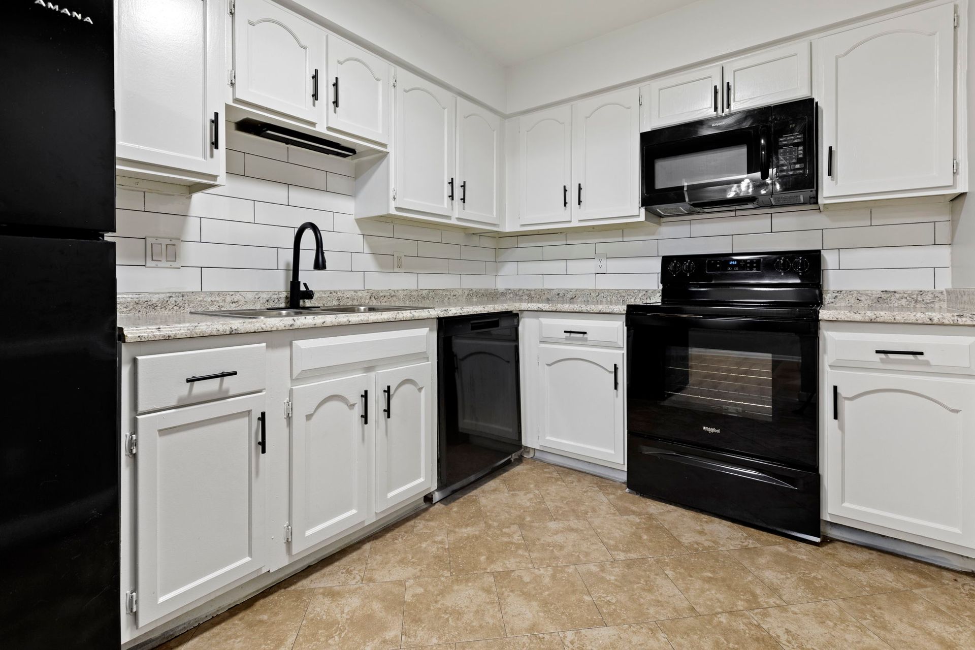 White kitchen cabinets, black appliances, and a neutral-toned floor.