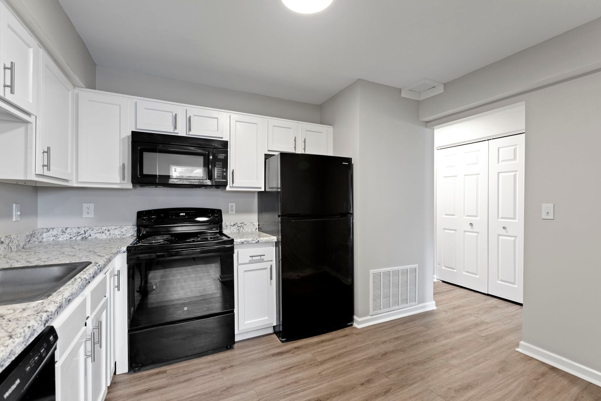 Kitchen with white cabinets, black appliances, and light gray walls.