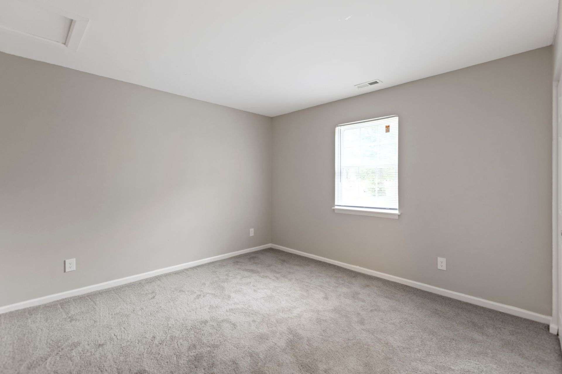 Empty bedroom with gray walls, carpet, and a window.