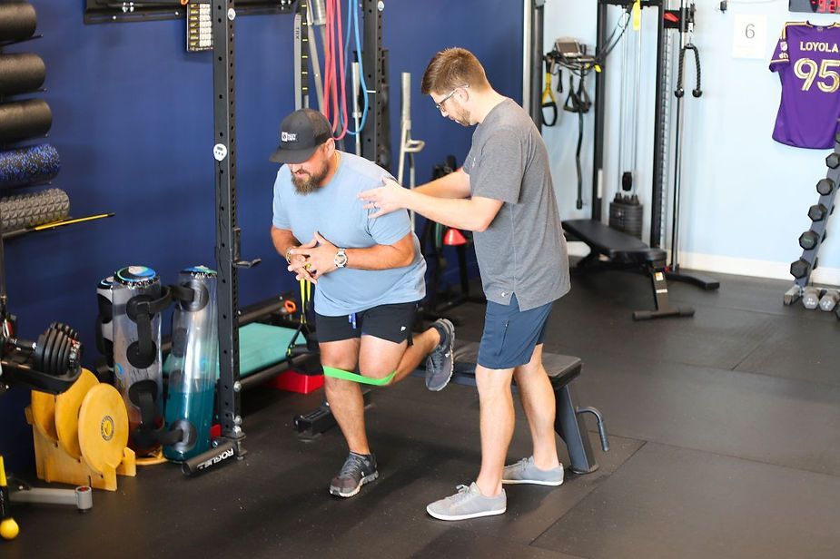 A man is doing exercises with a resistance band in a gym.
