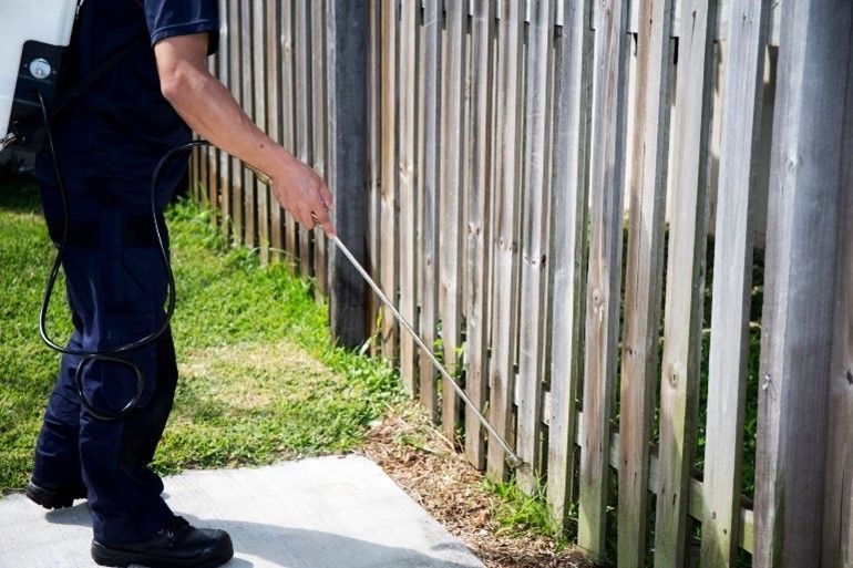 A man is spraying a fence. A man is spraying a fence.