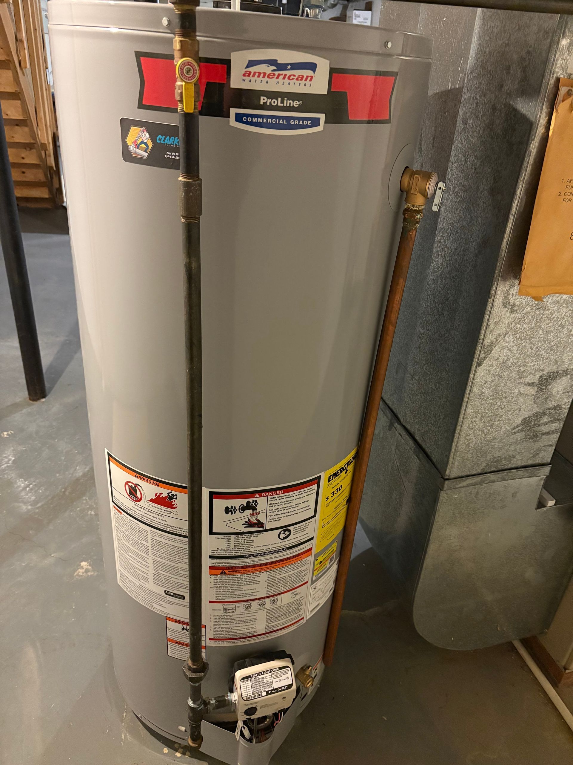 A water heater is sitting on the floor next to a wall.