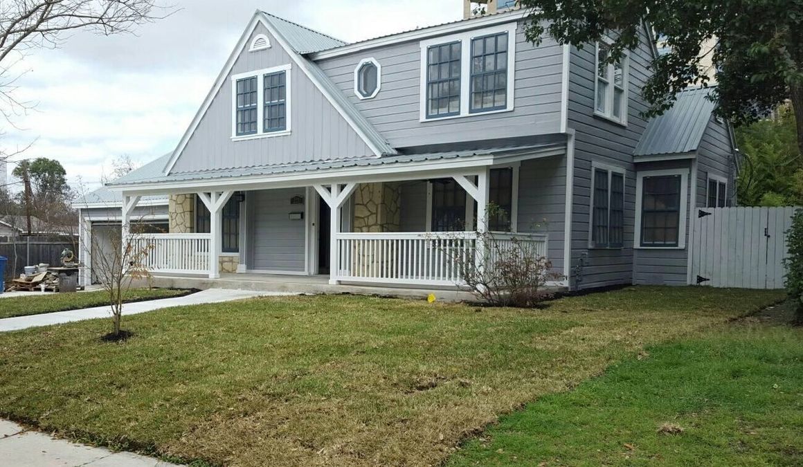 Gray two-story house with a porch and small front lawn.