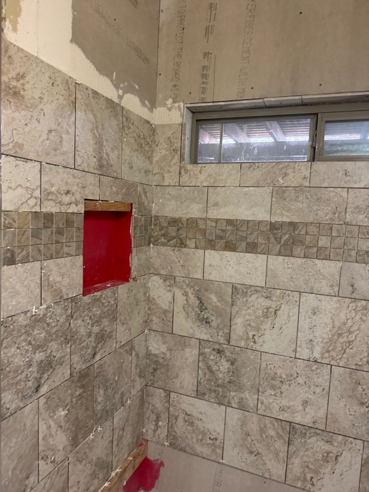 Tiled shower walls with a red niche, light brown tiles, and a horizontal decorative tile stripe.
