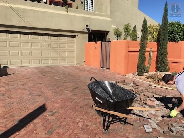 A man is working on a driveway next to a wheelbarrow