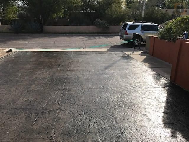 Two cars are parked in a driveway next to a brick wall.
