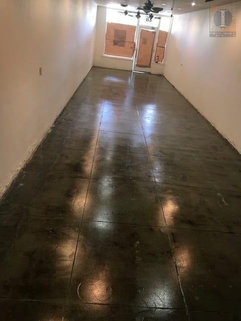 A long empty room with a concrete floor and white walls.