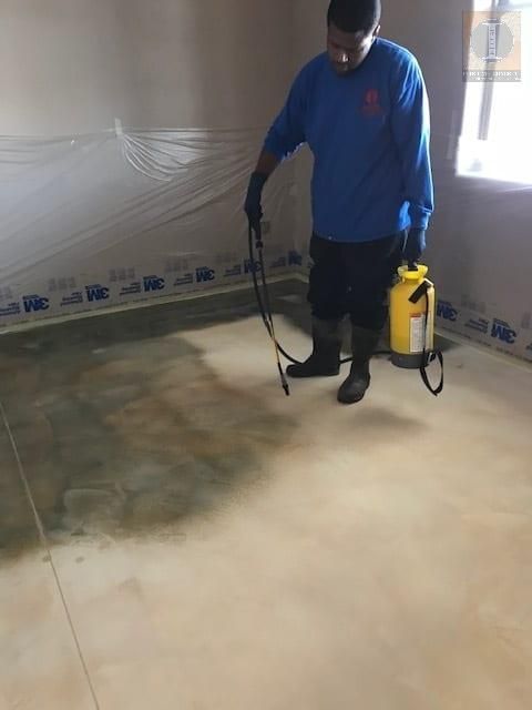 A man is spraying a floor with a yellow spray bottle.