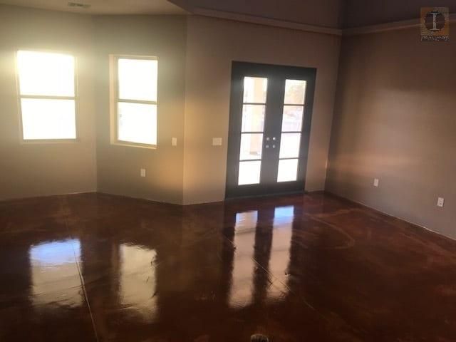 An empty room with a wooden floor and french doors