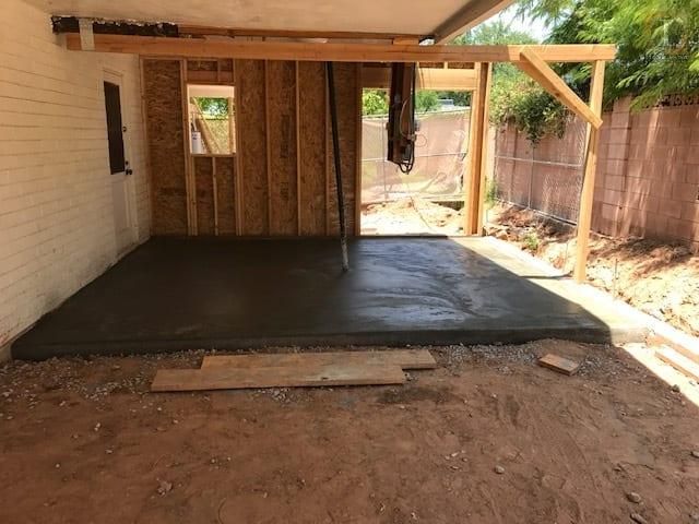 A concrete floor is being poured in a garage under construction.