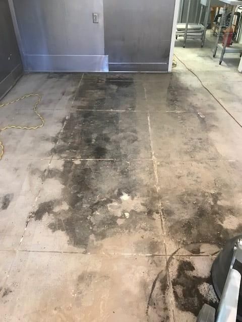 A dirty concrete floor in a room with a vacuum cleaner.