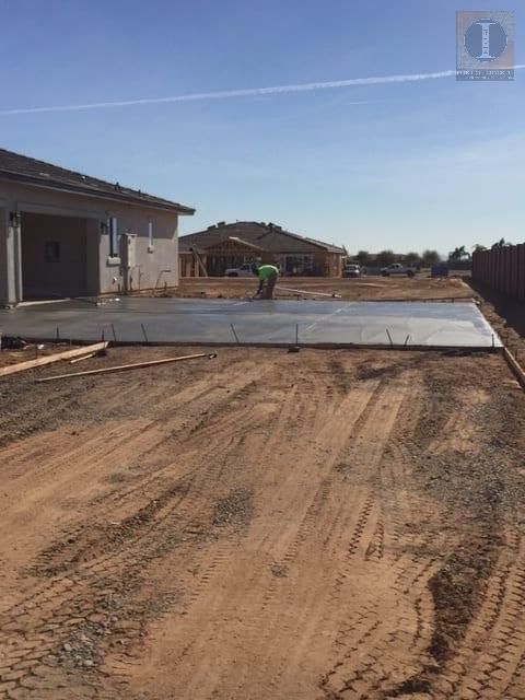 A man is working on a concrete driveway in front of a house.