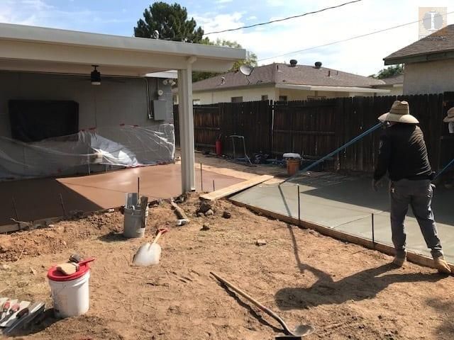 A man is standing in the dirt in front of a house.