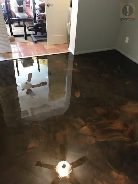 A room with a ceiling fan and a reflection of a ceiling fan in the floor.