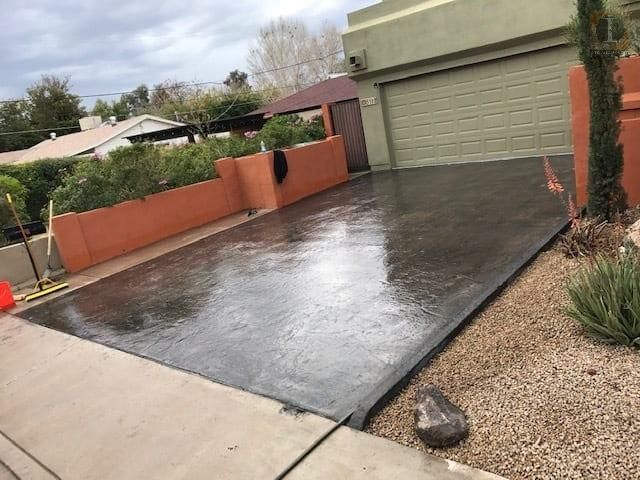 A concrete driveway is being painted in front of a house.