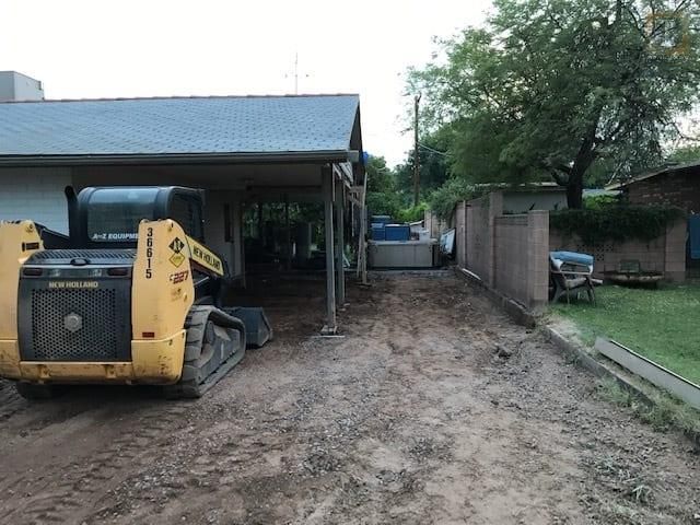 A yellow bulldozer is parked in front of a house.