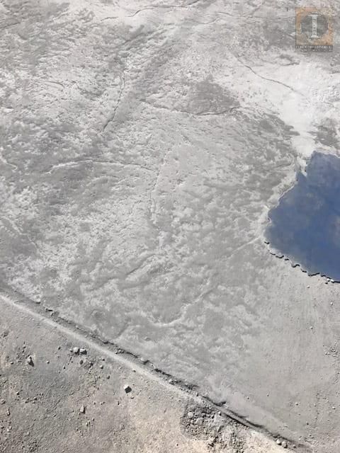 An aerial view of a concrete surface with a puddle in the middle of it.