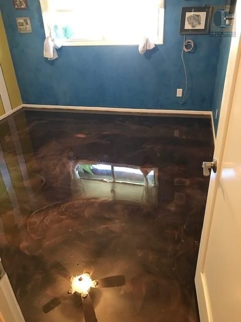 A room with a ceiling fan and a shiny floor.