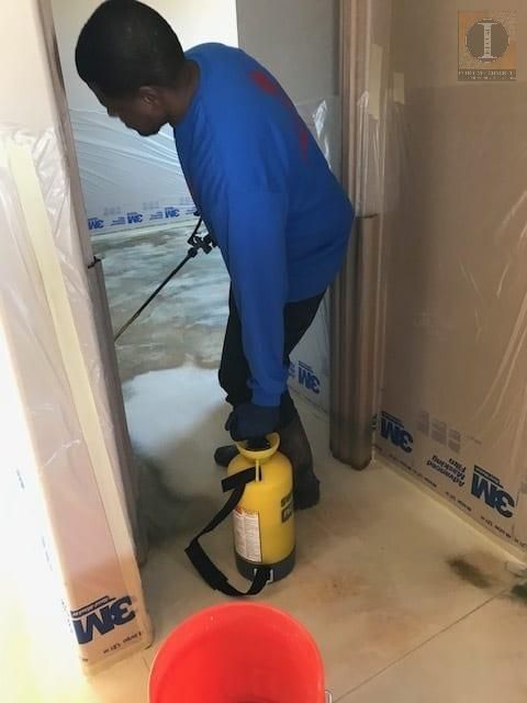 A man in a blue shirt is spraying something on the floor