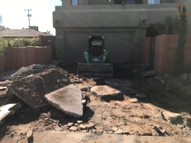 A bulldozer is moving rocks in front of a house
