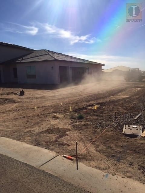 A house is being built on a dirt lot with a rainbow in the sky