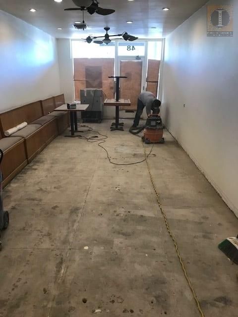 A man is working on the floor of a room with tables and chairs.