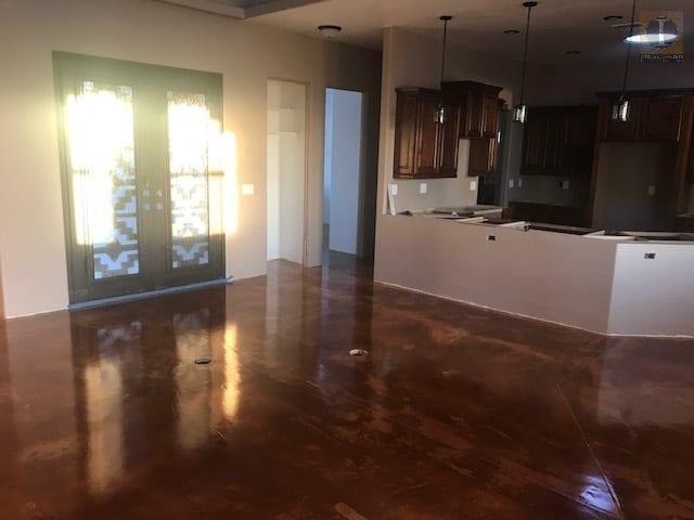 An empty room with a wooden floor and a kitchen in the background