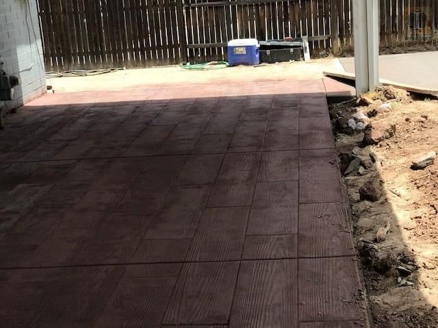 A patio with a fence and a blue cooler in the background.