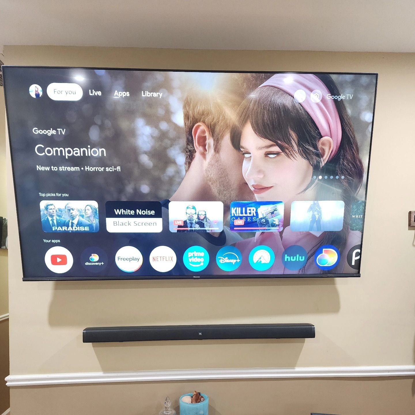 Large TV screen mounted on a wall displaying a streaming service interface, with a soundbar below.